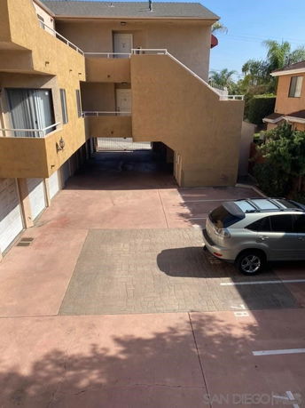 Outdoor parking area with a vehicle parked in front of a multi-level building.