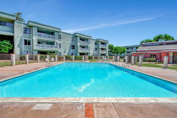 Outdoor swimming pool in front of a multi-story residential building.