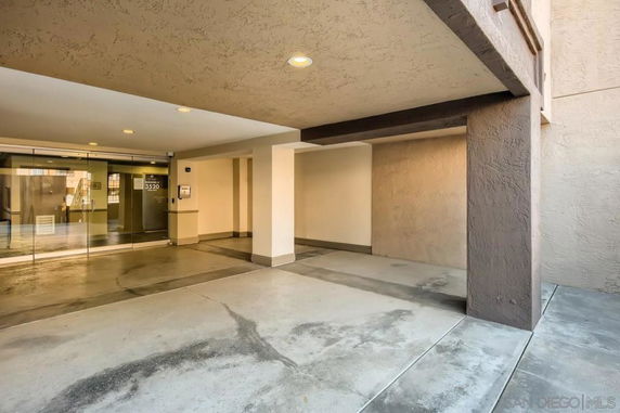 Covered parking area next to a building entrance with glass doors.
