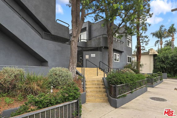 Front view of a multi-story building with stairs and greenery.