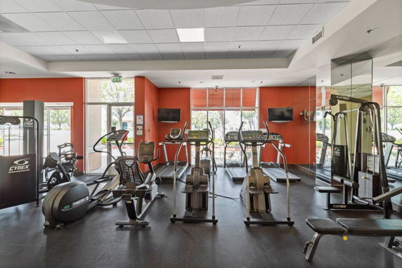Indoor gym area with various exercise equipment including treadmills, exercise bikes, and weight machines.