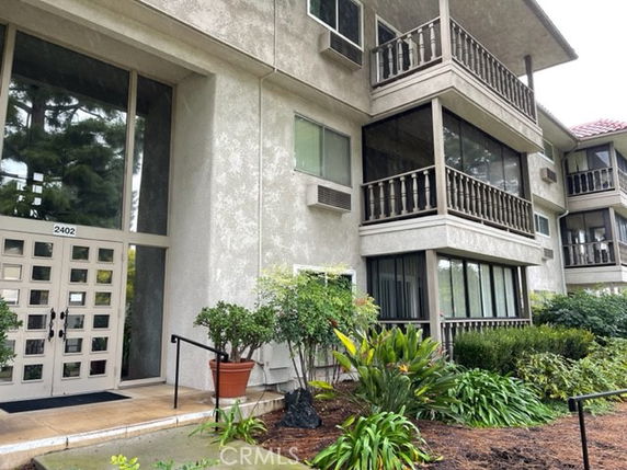Front view of a multi-story building with balconies and large windows.