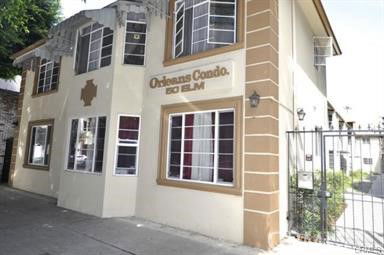 Front view of a two-story condominium building with multiple windows and gated entrance.