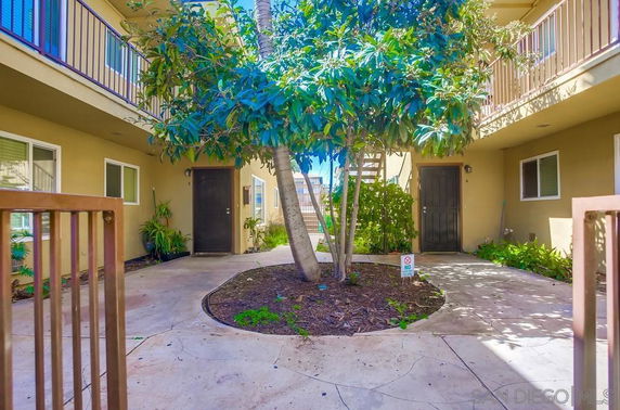 Courtyard view of a multi-unit residential building with balconies and trees.