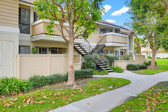Front view of a two-story residential building with balconies and exterior stairs.