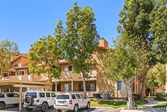 Front view of a multi-story residential building with beige exterior and visible balconies.