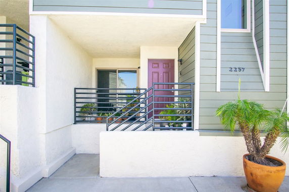Front view of a house entrance with a small porch and potted plants.