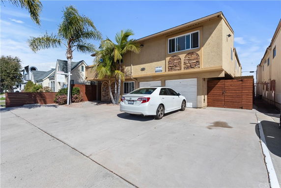 Driveway of a two-story house with a double garage and a car parked in front.