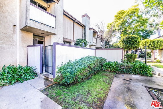 Front view of a condominium with a small patio and upper balcony.