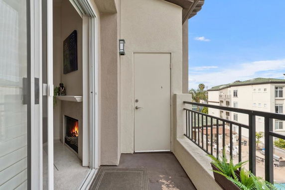 Small balcony with railing and views of other buildings in the background.