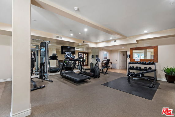 Indoor gym area with exercise equipment including treadmills, weights, and stationary bikes.