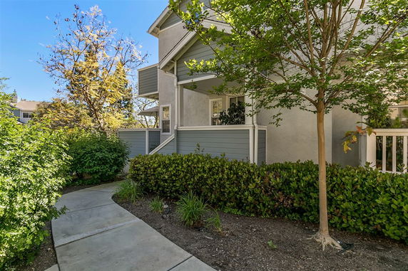 Front view of a two-story residential building with a walkway and trees in front.