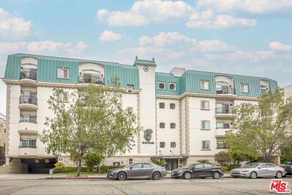 Front view of a multi-story building with green roof and balconies.