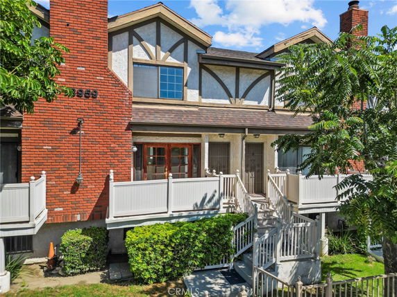 Front view of a multi-story house with brick exterior and white railing.