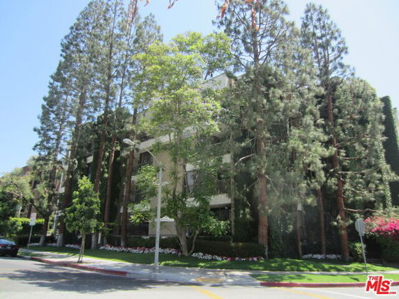 Front view of a multi-story building with tall trees.