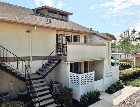 Front view of a two-story residential building with external stairs.