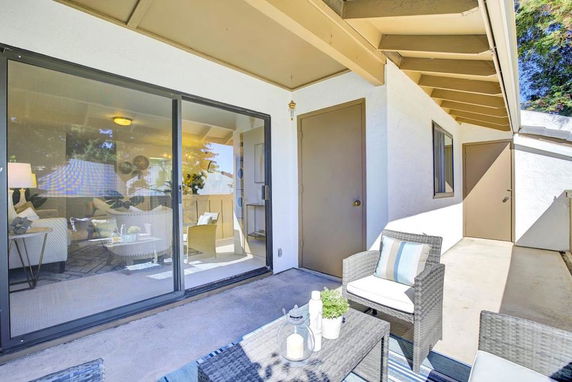 Exterior view of a house with patio furniture and sliding glass doors.