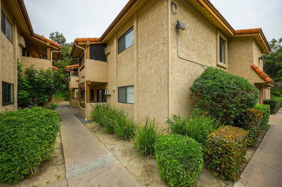 Front view of a two-story apartment building with stucco exterior and orange roof tiles.