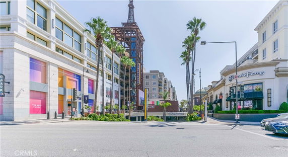 Front view of a commercial building with colorful window displays and palm trees.