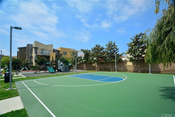 Basketball court with playground and residential buildings in the background.