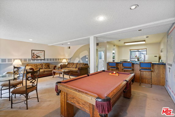 Interior view of a recreational area with a pool table, seating area, and a bar counter.