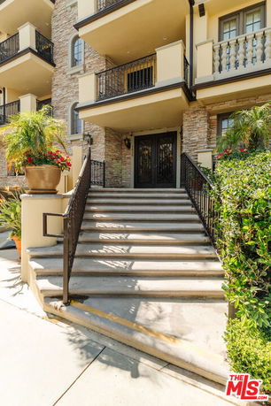 Front view of a multi-story building with stone facade and balcony railings.