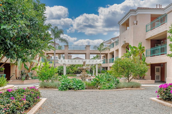 Front view of a multi-story apartment complex with balconies and greenery.