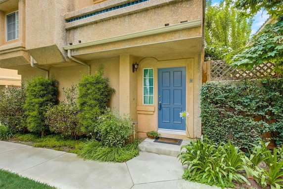 Front view of a house with a blue door and plants flanking the entrance.
