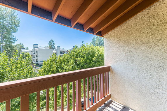 View from a balcony overlooking nearby buildings and trees.