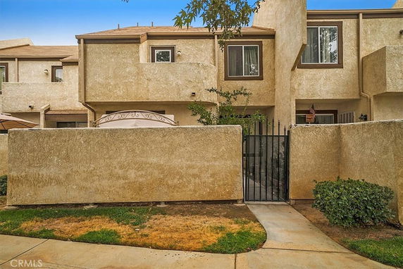 Front view of a two-story residential building with a gated entrance and stucco exterior.
