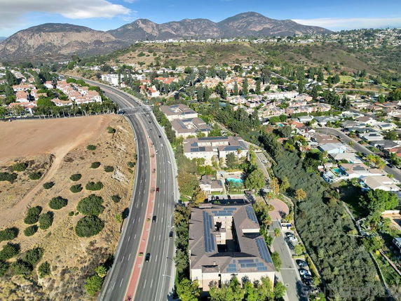 Aerial view showing a residential area with roads, houses, and distant mountains.