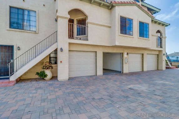 Exterior view of a building with multiple garage doors and a staircase.