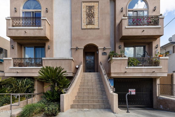 Front view of a multi-story building with balconies and stairs leading to the entrance.