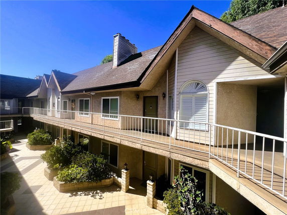 Front view of a two-story building with an exterior walkway and pitched roof.