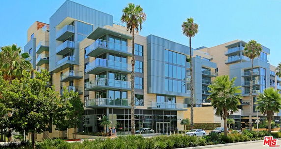 Front view of a modern multi-story building with large glass windows and balconies.