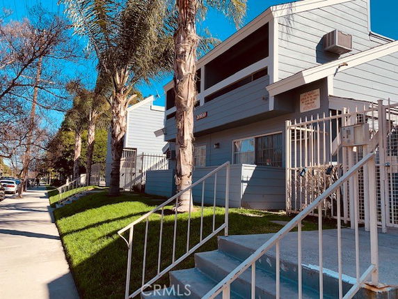 Front view of a multi-story residential building with grey exterior and railing.
