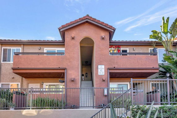 Front view of a two-story residential building with balconies and a central staircase.
