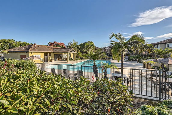 Outdoor swimming pool next to a building with a tiled roof and patio area.