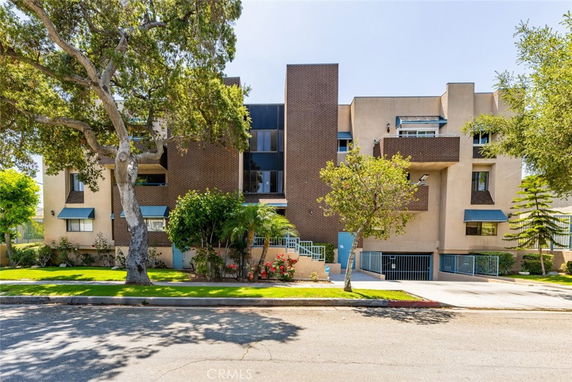 Front view of a multi-story residential building with distinct architectural features and surrounding greenery.