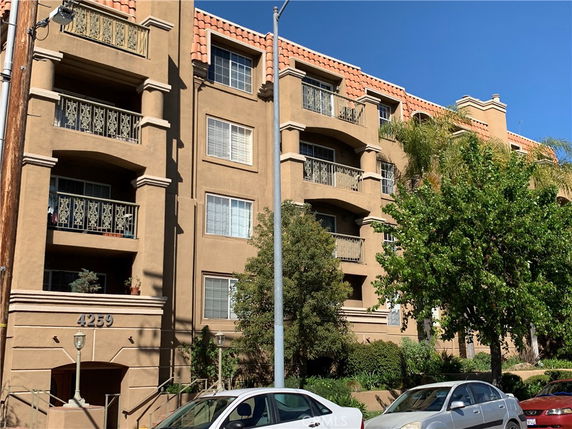 Front view of a multi-story residential building with balconies and tiled roof.