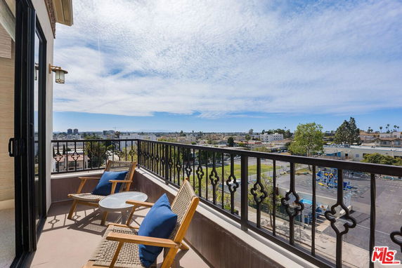Panoramic view from a balcony with chairs overlooking the cityscape.