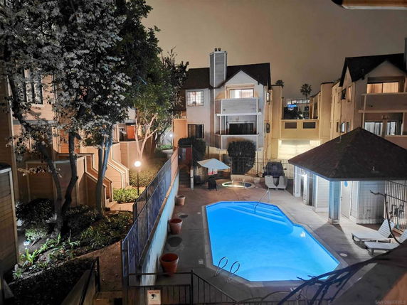 Swimming pool area surrounded by multi-story residential buildings at night.