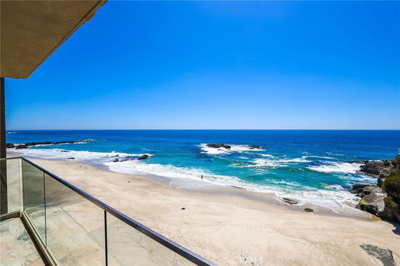 Panoramic view of a beach and ocean from a building balcony.