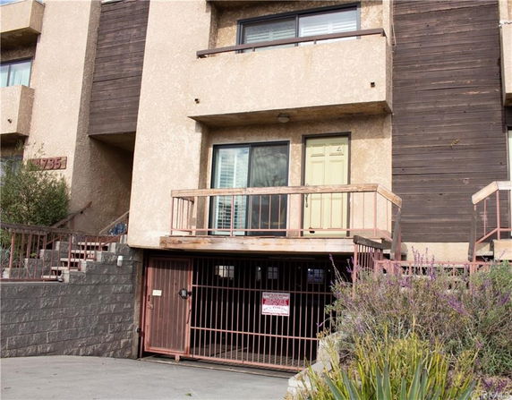 Front view of a multi-story building with a balcony and gated entry.