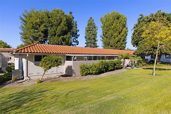 Side view of a single-story house with a tiled roof and surrounding greenery.
