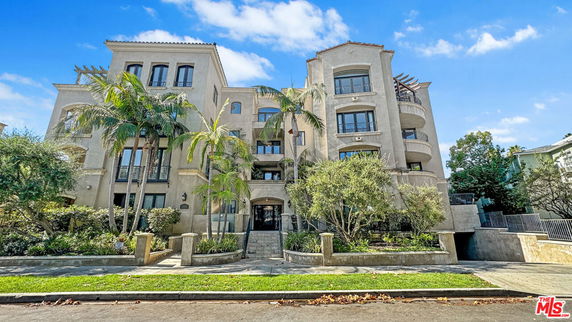 Front view of a multi-story residential building with balconies and a gated entrance.