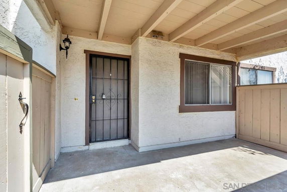 Front view of a house entrance with a covered porch and a metal door.