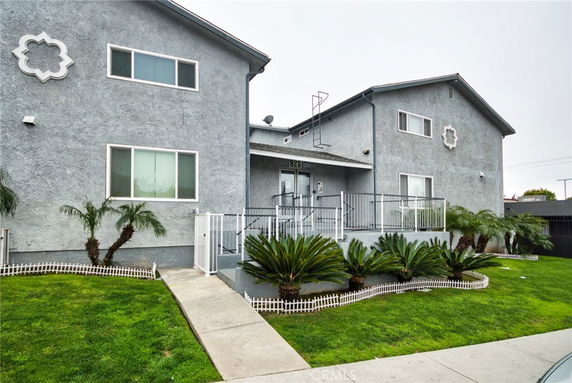 Front view of a two-story house with a balcony and decorative window designs.