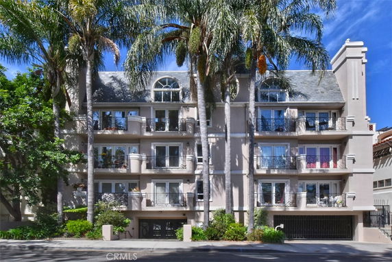 Front view of a multi-story residential building with balconies and a gated entrance.