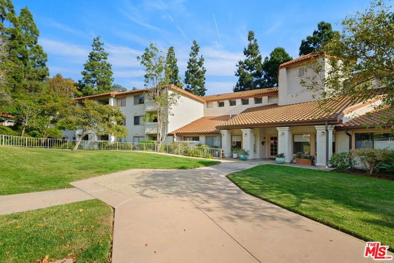 Front view of a multi-story building with a tiled roof and landscaped surroundings.